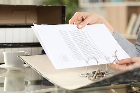 145698421 close up of girl hands putting documents on a ring binder at home